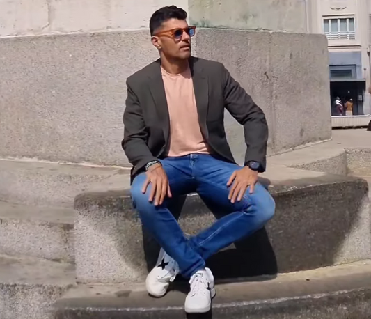 hombre con americana, camiseta debajo rosa y vaqueros mostrando cómo combinar la ropa de entretiempo